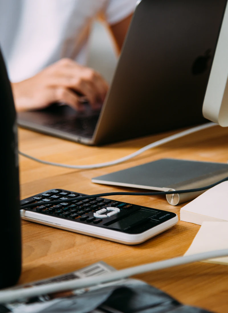 An accountant working at a laptop beside a calculator and notebook